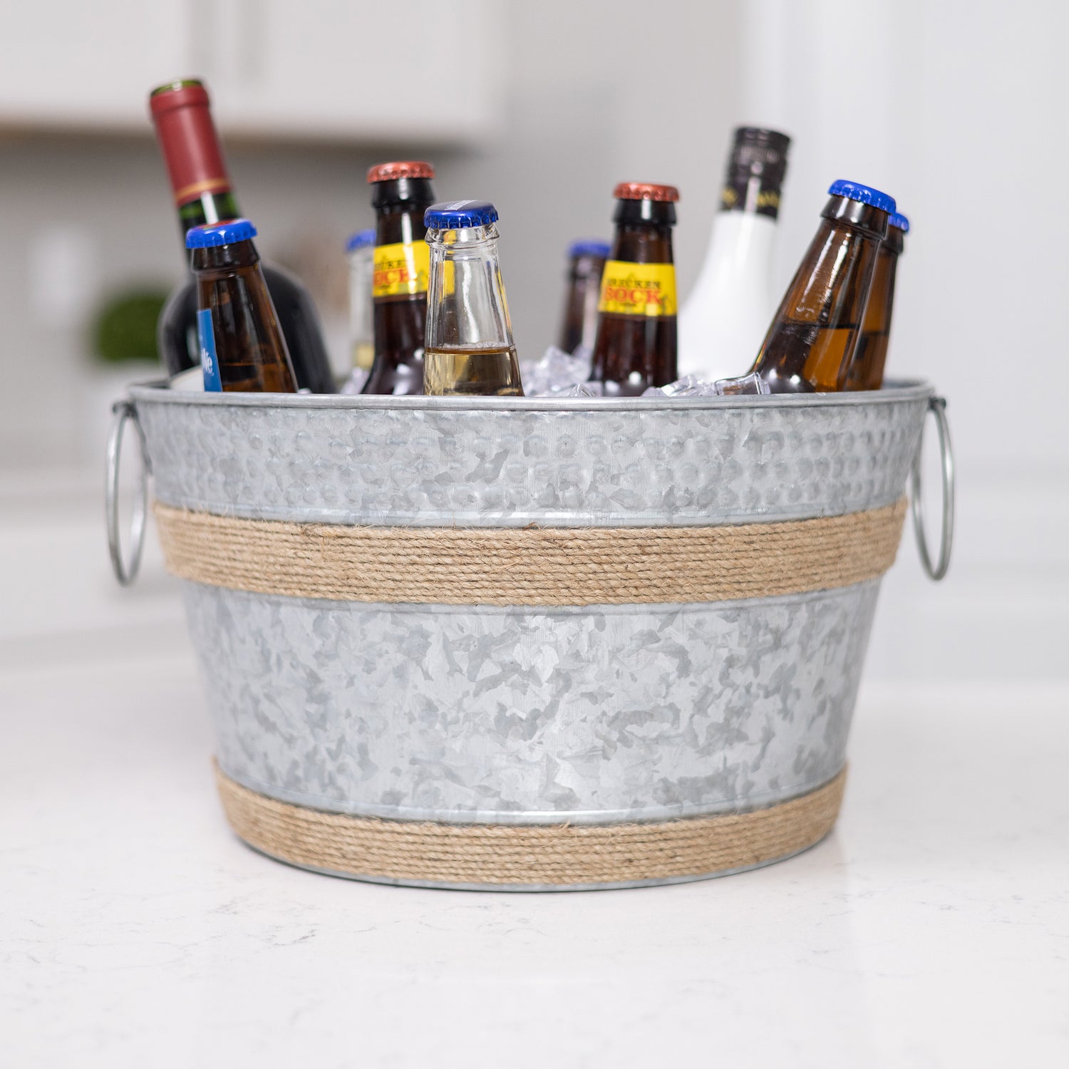 Introducing our galvanized ice bucket with farmhouse flair! Crafted from rustic galvanized material and adorned with twine rope accents, this bucket seamlessly blends farmhouse style with functionality. Perfect for any home setting, it's an ideal addition to your kitchen or a thoughtful gift. Complete the charm by including a personalized message, making it a distinctive and heartfelt present for weddings, anniversaries, or housewarmings. 