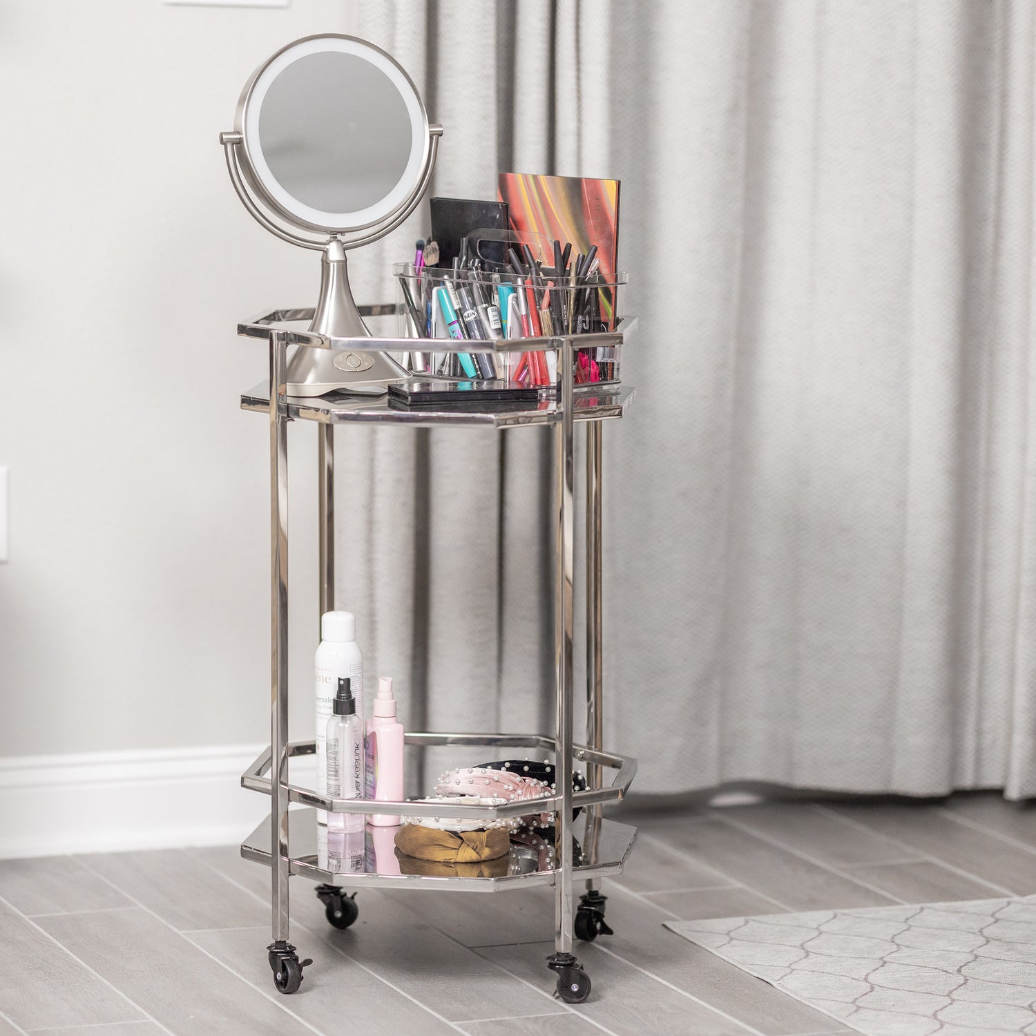 Portable vanity includes wheels for easy rolling.  Has two shelves to hold cosmetics or other personal items.